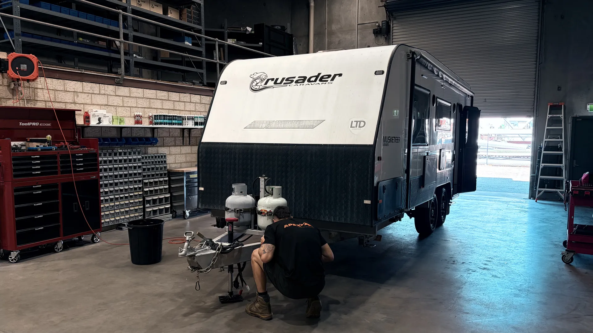 A Crusader caravan in the Apex workshop with a technician working at the A-frame