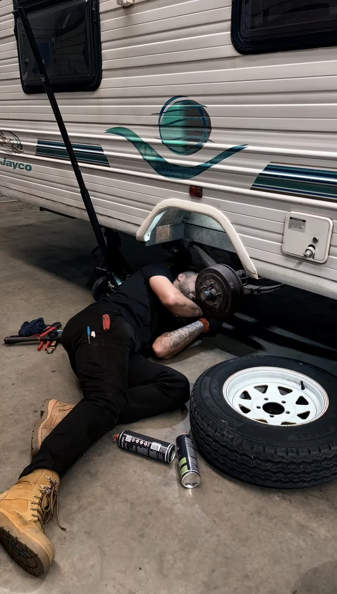 Mark underneath Jayco caravan inspecting bearings